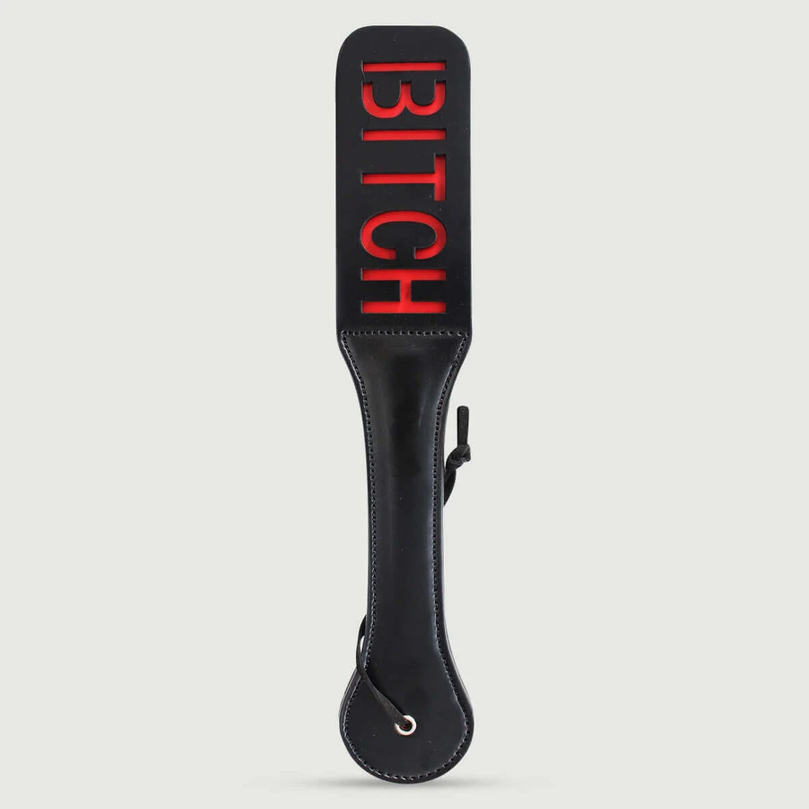 Paddle en simili cuir de la série Domme avec découpe « BITCH » et doublure rouge - Noir